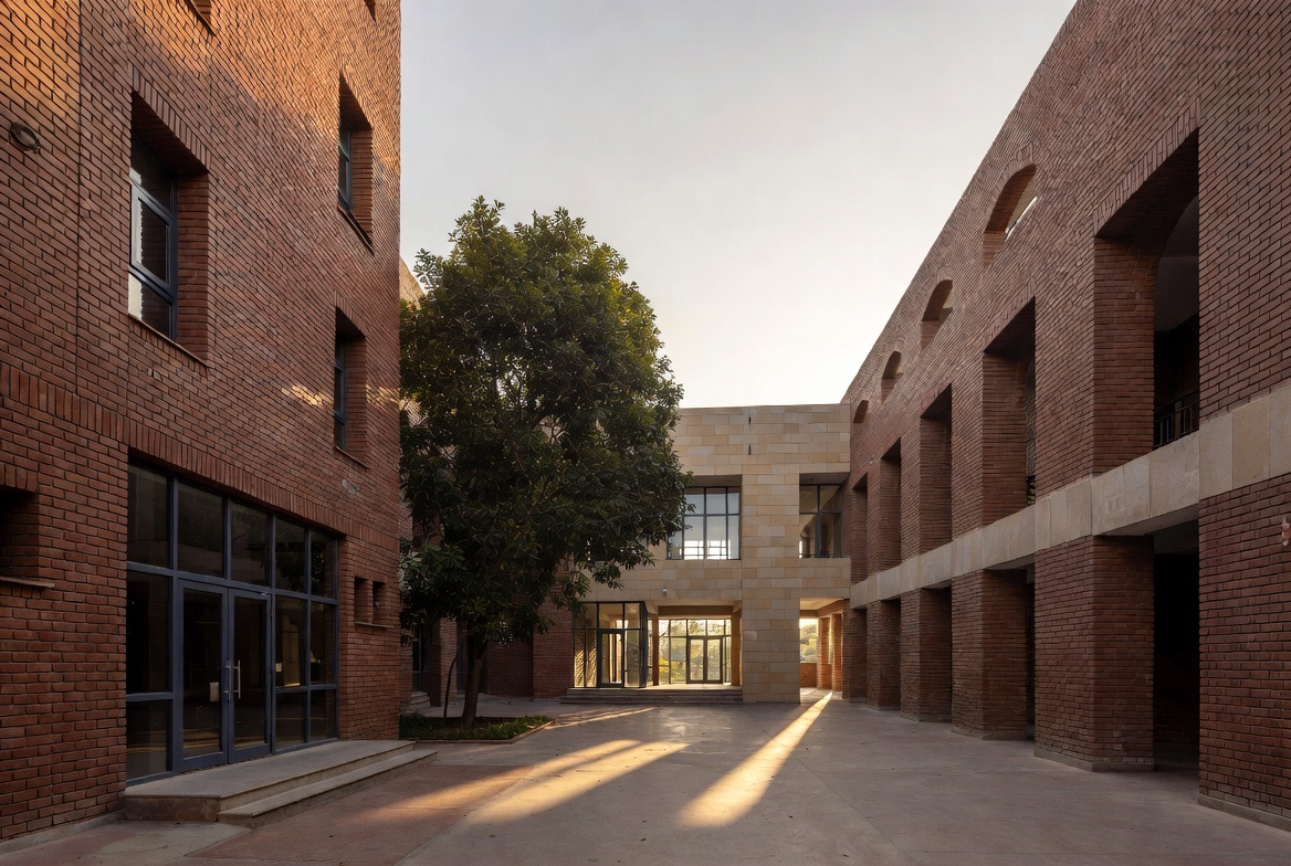Neeva School modern campus courtyard with red brick architecture and trees